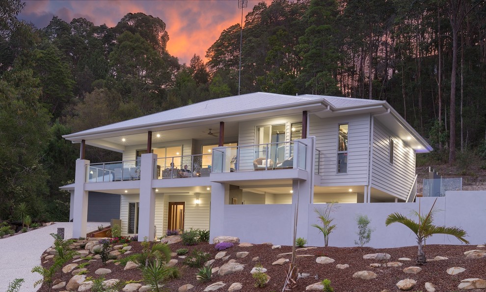 На фото: белый дом среднего размера в морском стиле с разными уровнями и комбинированной облицовкой