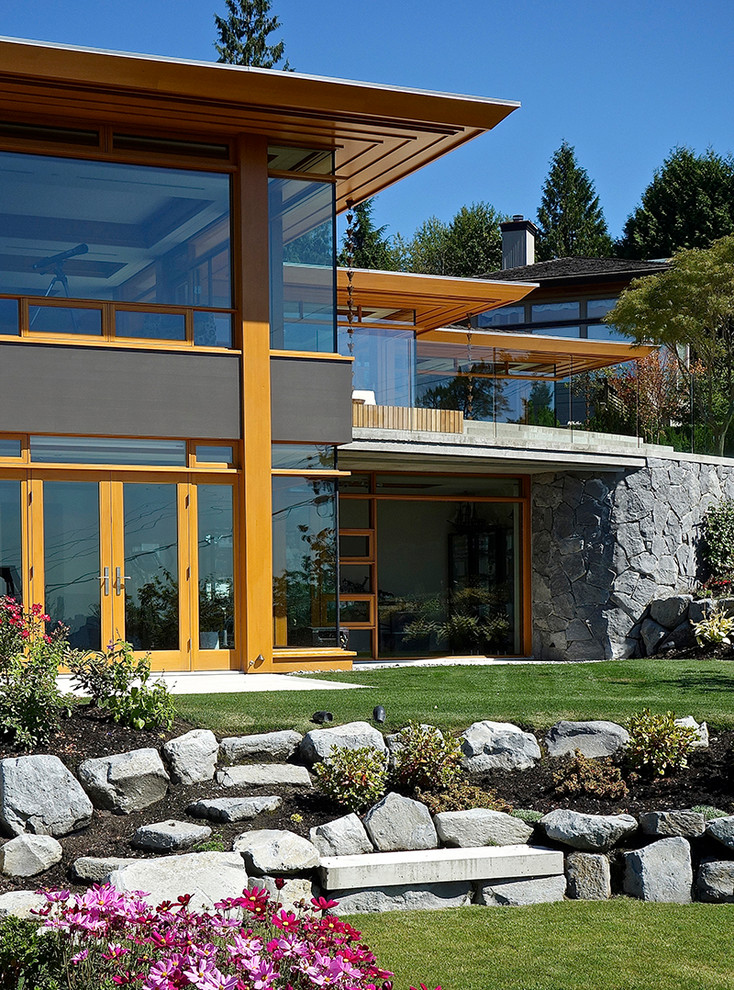 Idée de décoration pour une grande façade de maison design en verre à un étage avec un toit à quatre pans.