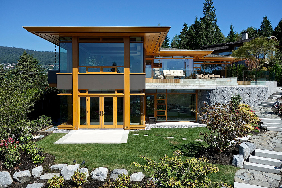 На фото: двухэтажный, стеклянный частный загородный дом в современном стиле с вальмовой крышей