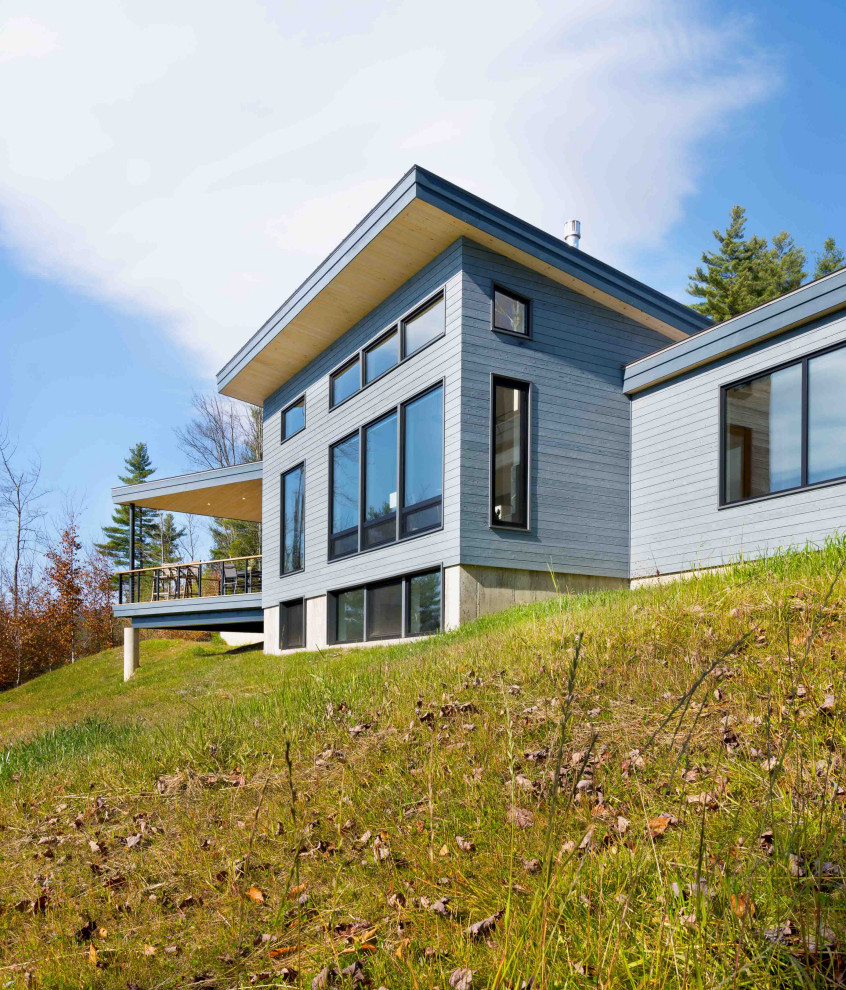 На фото: большой, двухэтажный, деревянный, серый частный загородный дом в стиле модернизм