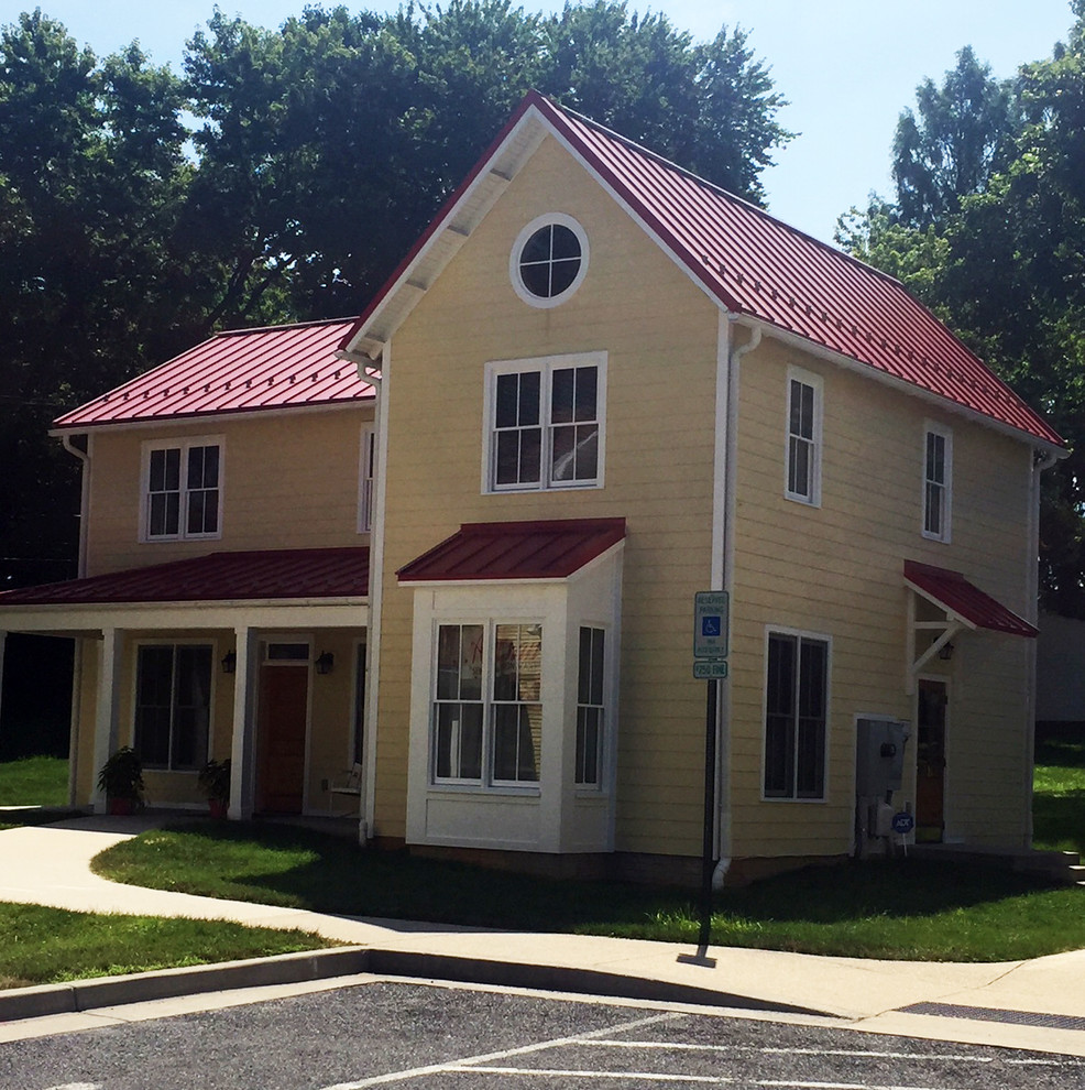 Mittelgroße, Zweistöckige Landhausstil Holzfassade Haus mit gelber Fassadenfarbe, Walmdach, Blechdach und rotem Dach in Baltimore