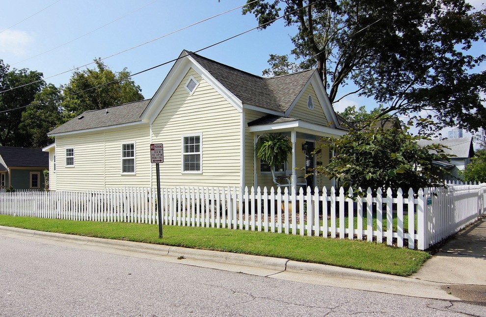 Aménagement d'une petite façade de maison jaune contemporaine en bois et bardage à clin de plain-pied avec un toit en appentis, un toit en shingle et un toit gris.