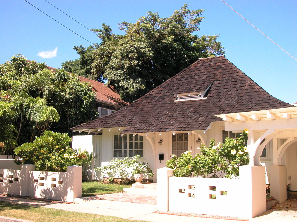 Cette photo montre une façade de maison blanche exotique en bois de taille moyenne et de plain-pied avec un toit à quatre pans.