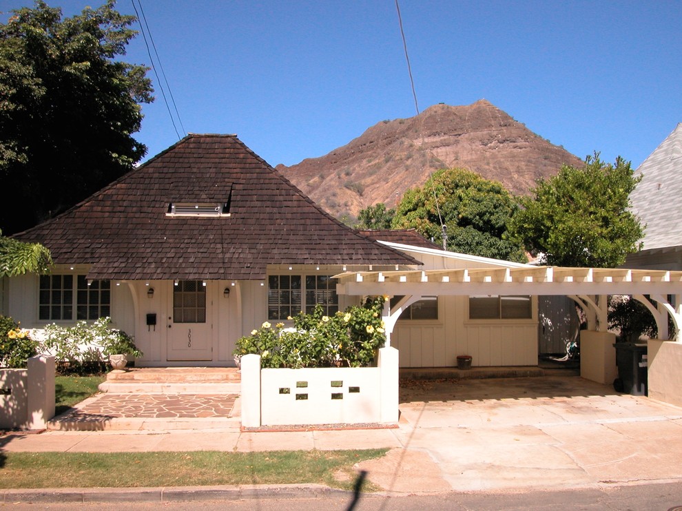 Immagine della facciata di una casa bianca tropicale a un piano di medie dimensioni con rivestimento in legno e tetto a padiglione