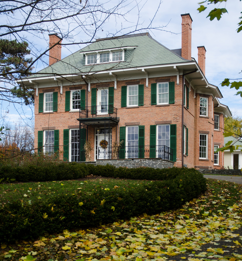 This is an example of a large and red traditional brick detached house in Boston with a hip roof, three floors and a shingle roof.