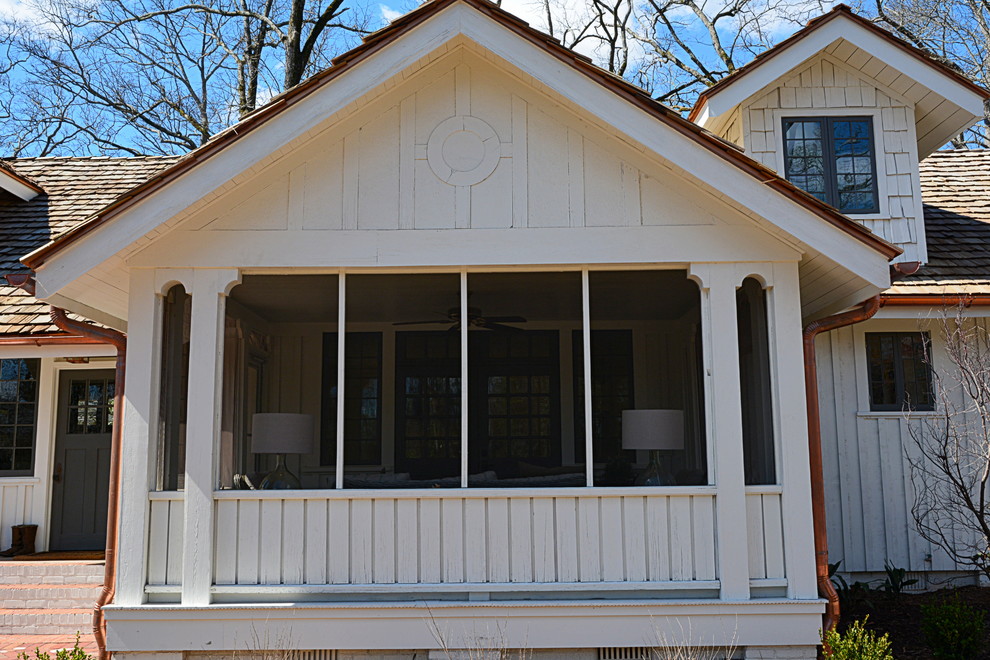 Imagen de fachada de casa blanca campestre grande de dos plantas con revestimiento de madera, tejado a dos aguas y tejado de teja de madera