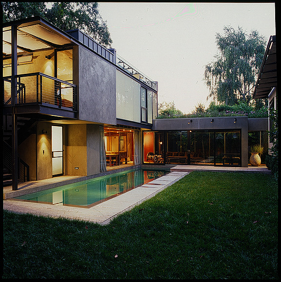 Idéer för ett mellanstort modernt beige hus, med två våningar, stuckatur, platt tak och tak i metall