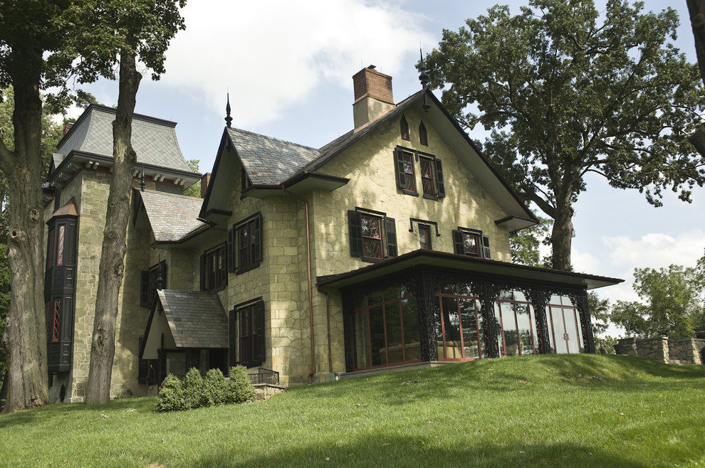 На фото: огромный, трехэтажный, зеленый дом в классическом стиле с облицовкой из камня с