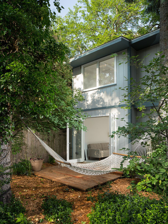 Réalisation d'une façade de maison verte tradition de taille moyenne et à un étage avec un revêtement en vinyle et un toit plat.