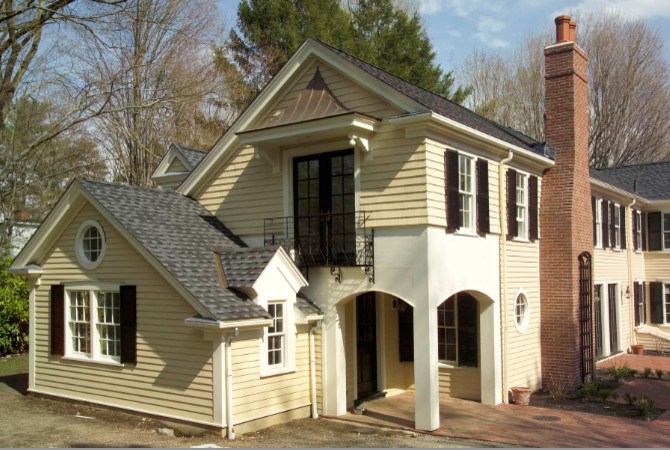 Aménagement d'une grande façade de maison jaune classique en bois à un étage avec un toit à deux pans.
