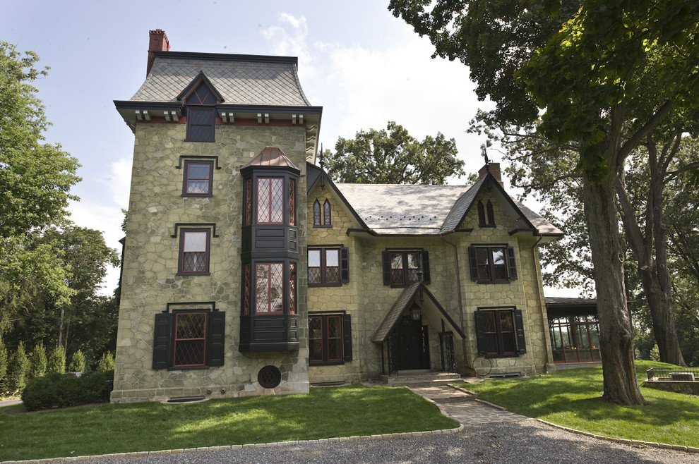 Photo of an expansive and green victorian house exterior in Philadelphia with stone cladding and three floors.