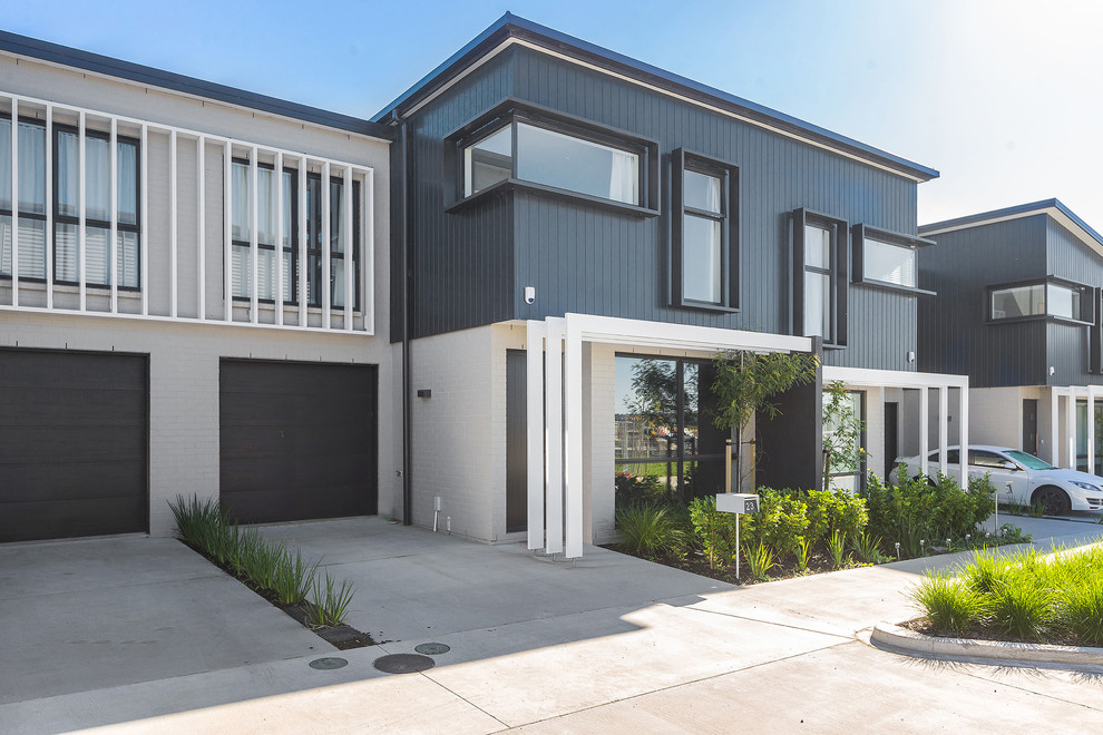 Medium sized and white contemporary two floor terraced house in Auckland with mixed cladding, a flat roof and a metal roof.