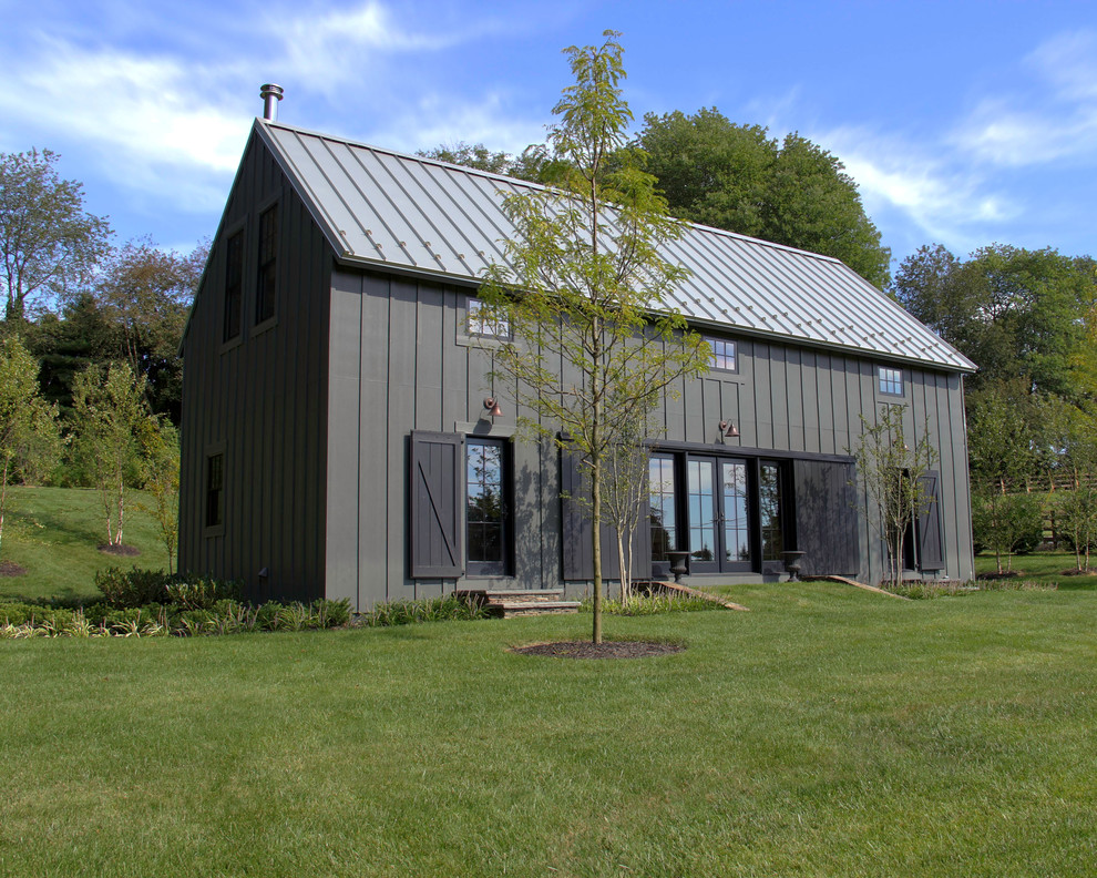 Aménagement d'une petite façade de maison grise campagne en panneau de béton fibré à un étage avec un toit à deux pans et un toit en métal.