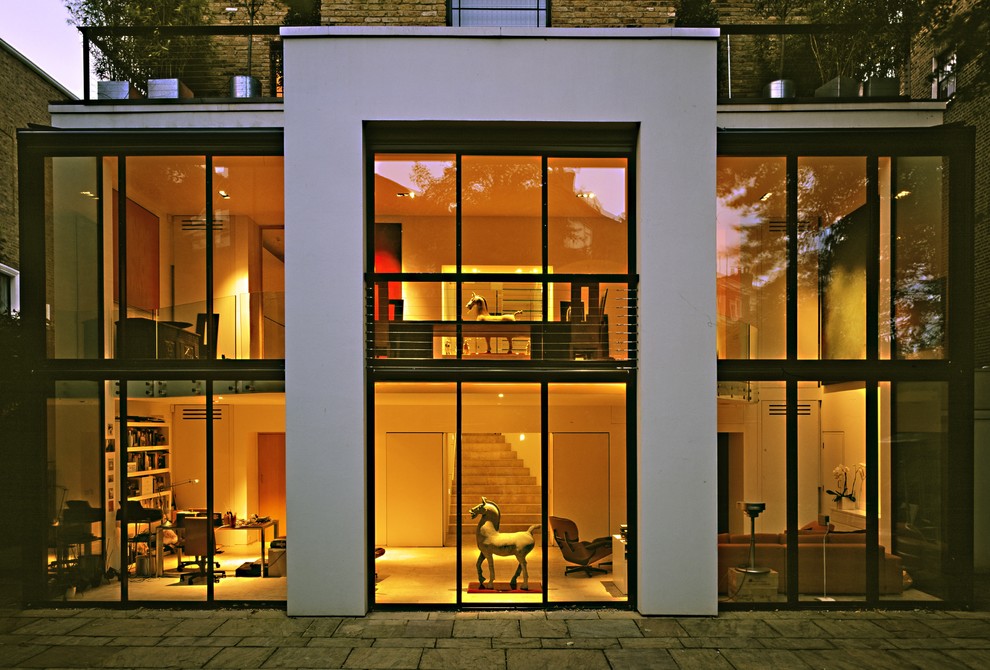 ロンドンにあるコンテンポラリースタイルのおしゃれな二階建ての家 (ガラスサイディング) の写真