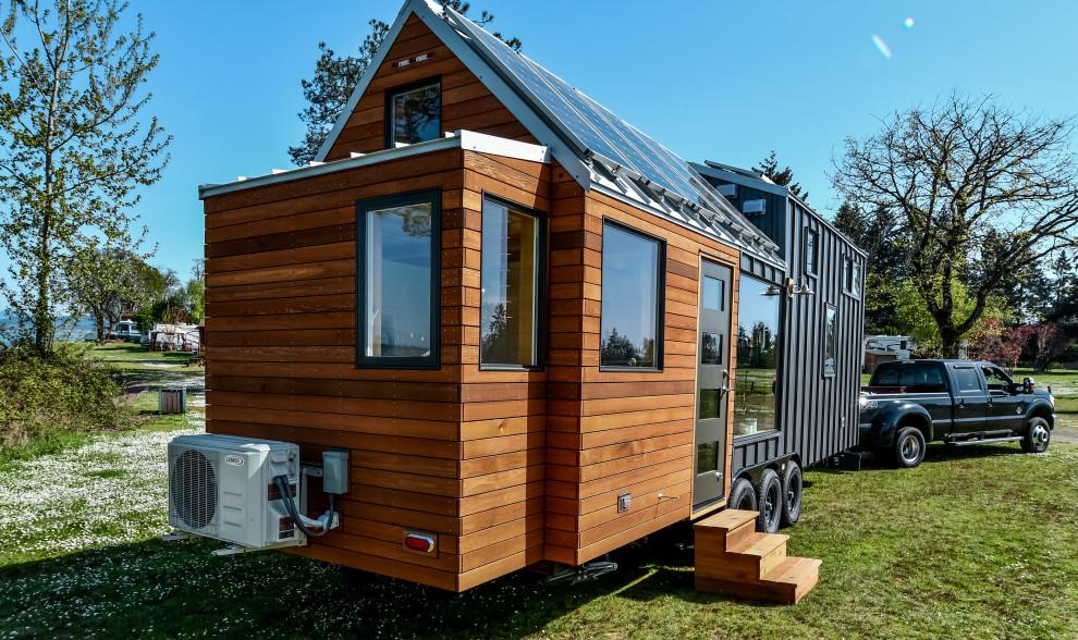 На фото: маленький, двухэтажный, деревянный мини дом в стиле кантри с двускатной крышей, металлической крышей и серой крышей для на участке и в саду с