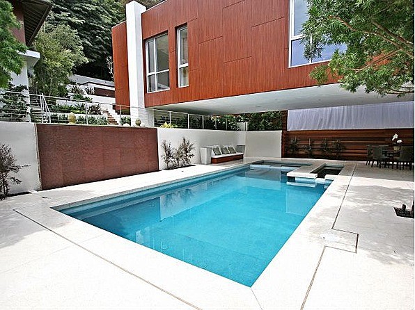 Diseño de piscinas y jacuzzis alargados contemporáneos grandes en forma de L en patio trasero con losas de hormigón