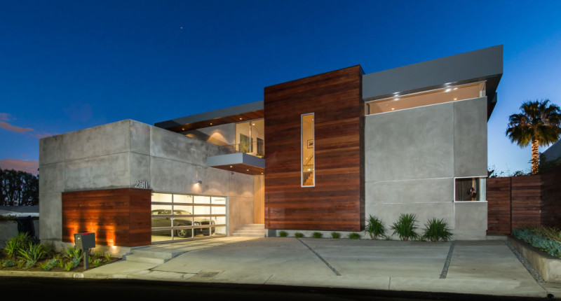 Cette image montre une grande façade de maison grise minimaliste en verre à un étage.