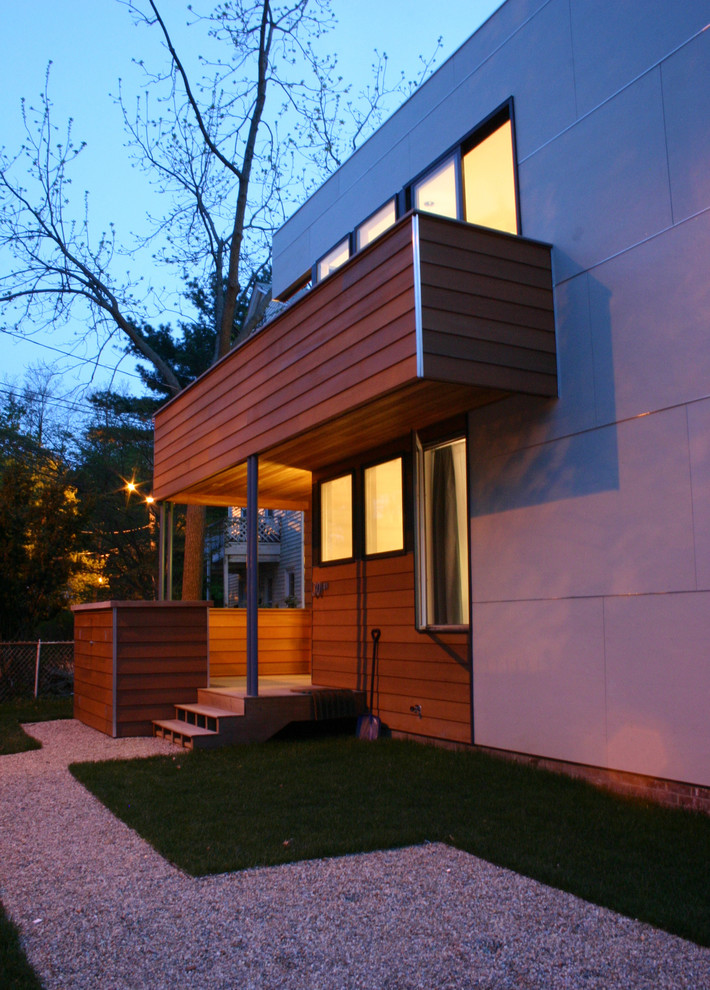 Cette image montre une grande façade de maison grise minimaliste en bois à un étage.