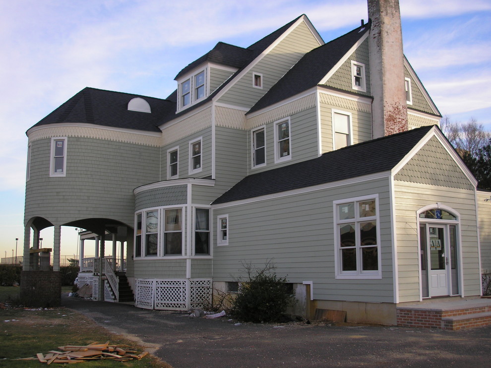 Inspiration for a large timeless green three-story mixed siding gable roof remodel in New York