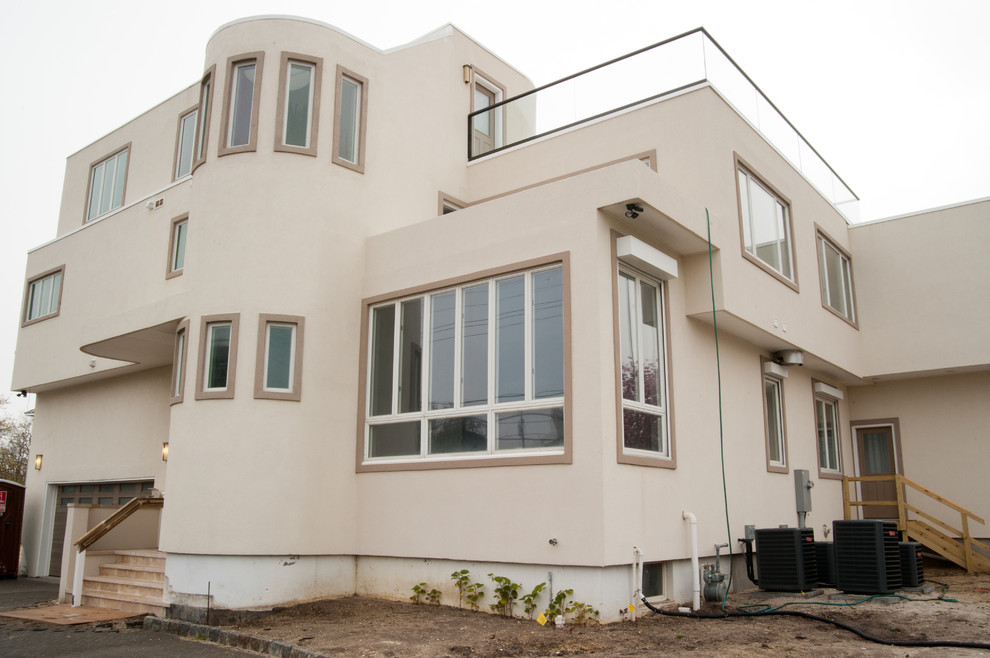 Свежая идея для дизайна: трехэтажный, бежевый дом среднего размера в современном стиле с облицовкой из цементной штукатурки и плоской крышей - отличное фото интерьера