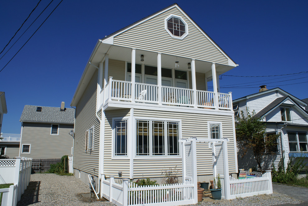 This is an example of a medium sized and beige traditional two floor house exterior in New York with vinyl cladding and a pitched roof.