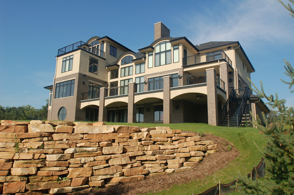 Immagine della facciata di una casa ampia beige contemporanea a tre piani con rivestimento in mattoni