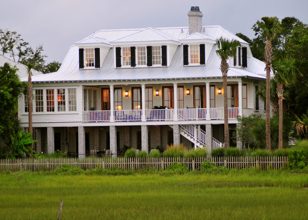 Inspiration for a world-inspired house exterior in Charleston with wood cladding, a half-hip roof, a metal roof and a white roof.