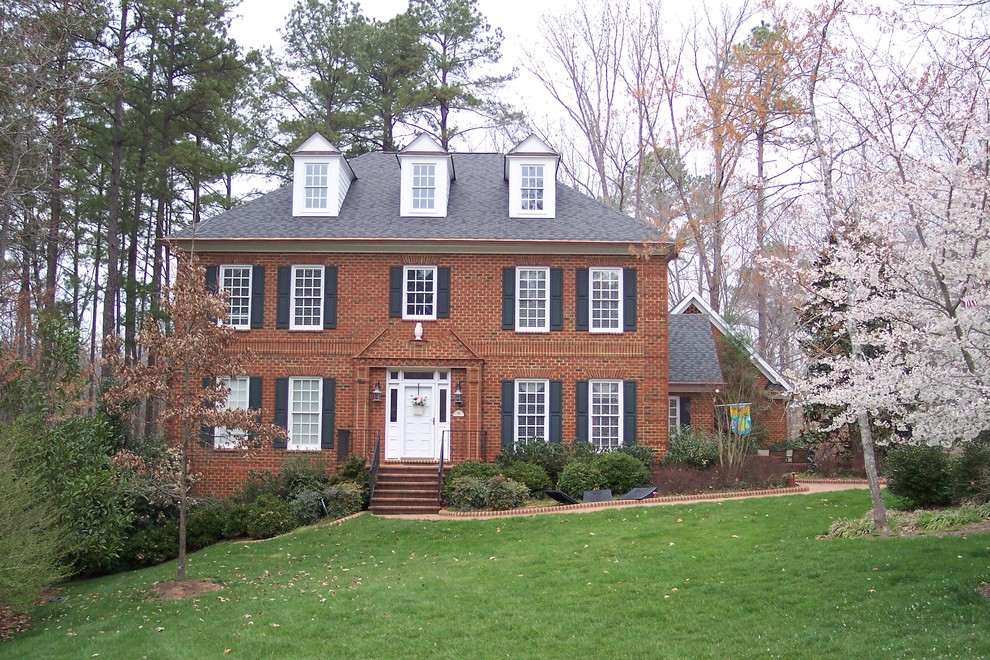 Photo of a large classic brick house exterior in Raleigh with three floors and a hip roof.