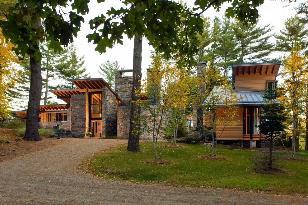 Imagen de fachada marrón moderna grande de tres plantas con revestimiento de piedra y tejado de un solo tendido