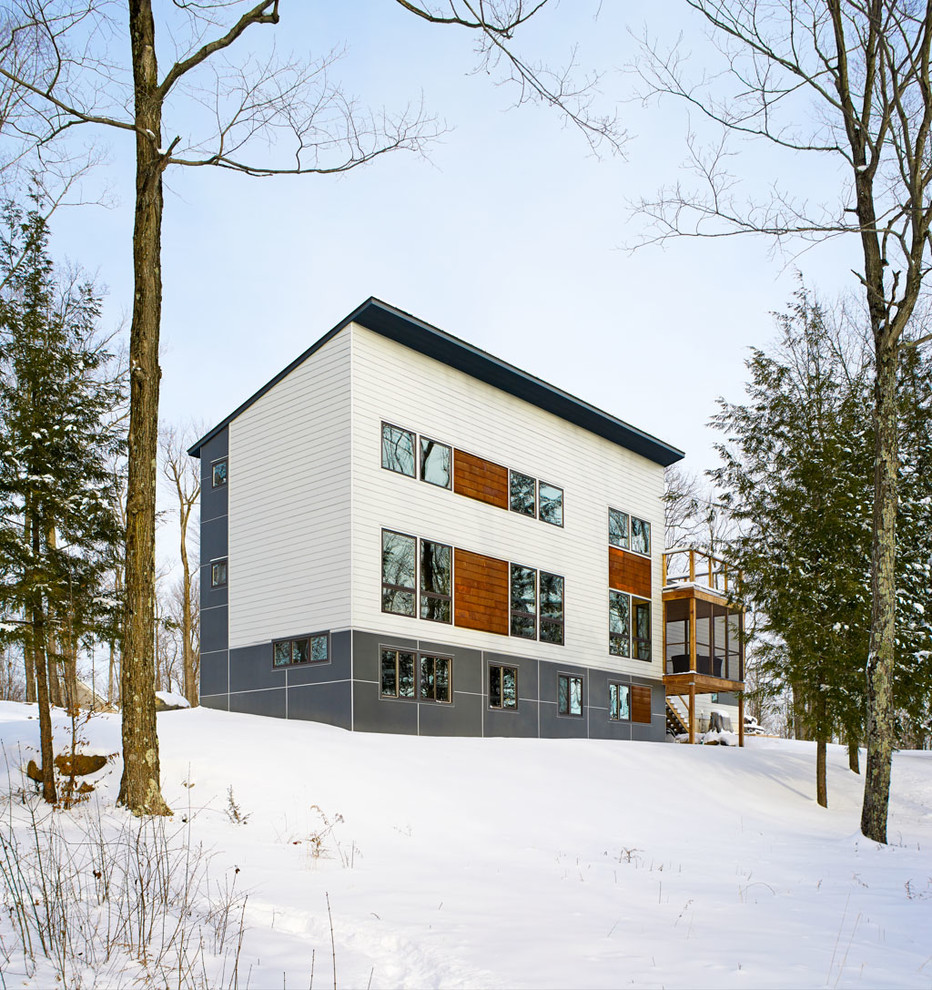 На фото: трехэтажный дом в современном стиле с комбинированной облицовкой и односкатной крышей с