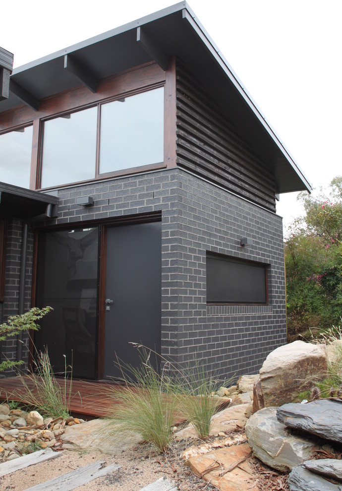 Idee per la facciata di una casa nera moderna a un piano di medie dimensioni con rivestimento in mattoni e tetto piano