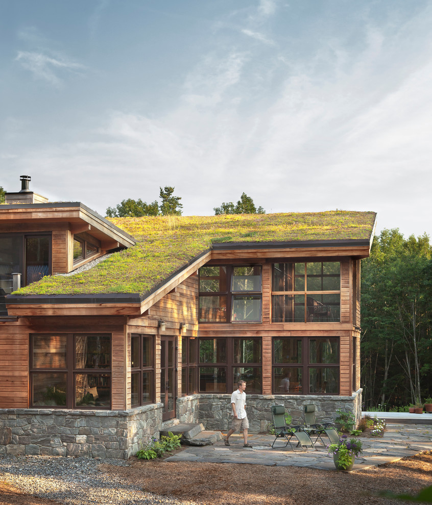 Foto på ett stort funkis brunt trähus, med pulpettak och levande tak