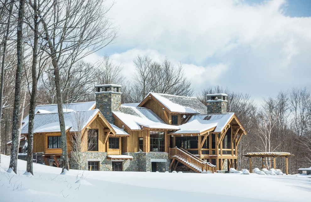 На фото: трехэтажный, коричневый частный загородный дом в стиле рустика с комбинированной облицовкой, двускатной крышей и крышей из гибкой черепицы