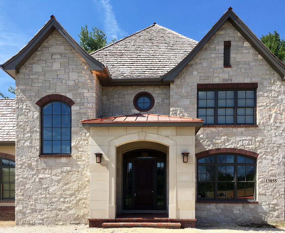 Large elegant beige two-story stone house exterior photo in Other with a hip roof and a shingle roof
