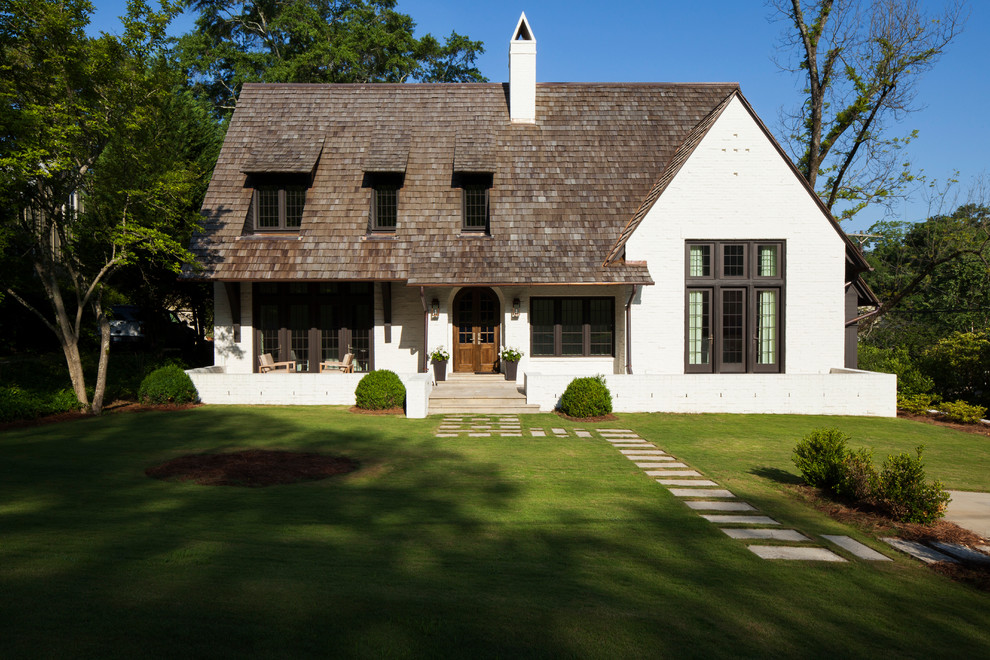Foto della villa bianca classica a due piani di medie dimensioni con tetto a capanna, rivestimento in mattoni e copertura a scandole