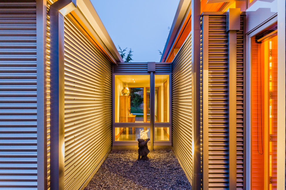 На фото: маленький, одноэтажный, серый дом в современном стиле с облицовкой из металла и плоской крышей для на участке и в саду с