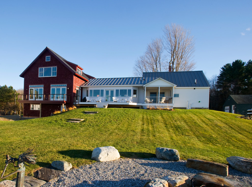 На фото: большой, двухэтажный, кирпичный, красный частный загородный дом в стиле кантри с двускатной крышей и металлической крышей с