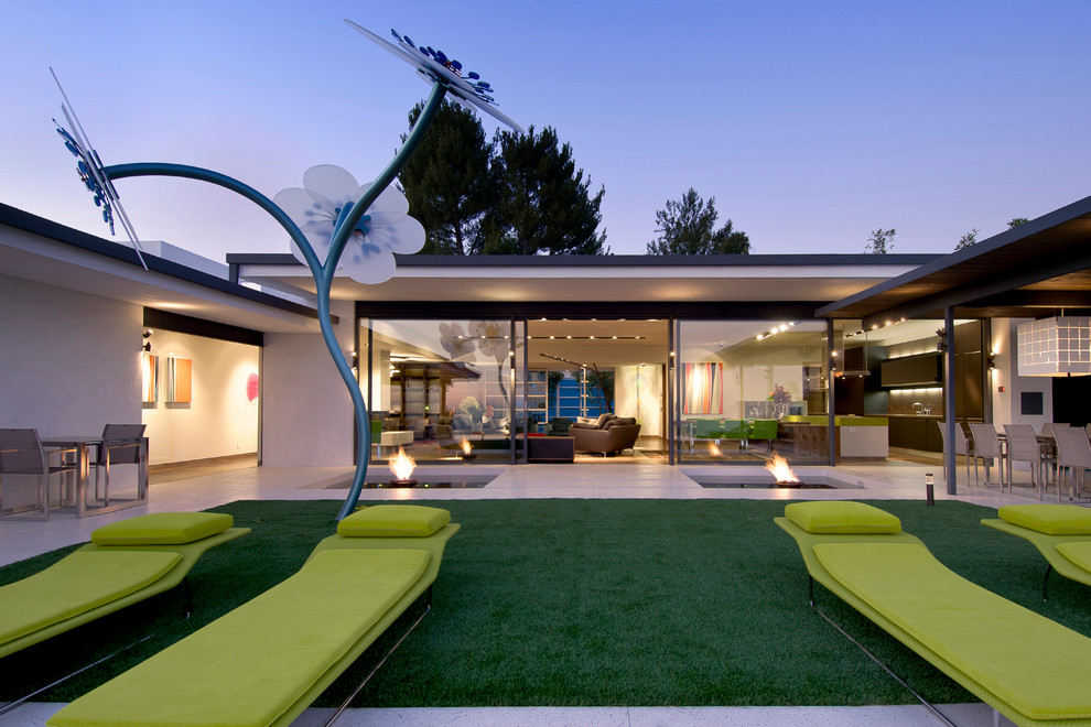 Esempio di un ampio patio o portico minimal dietro casa con un focolare, piastrelle e un tetto a sbalzo