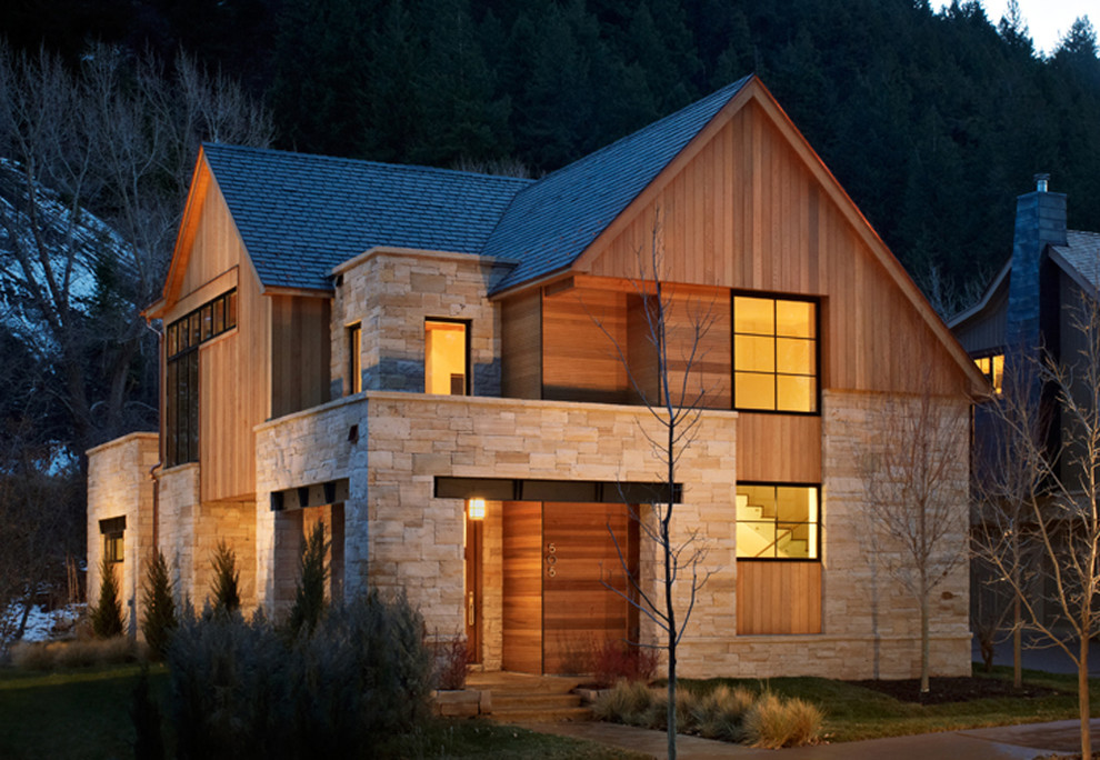 Idée de décoration pour une grande façade de maison marron design en bois à un étage avec un toit à quatre pans.