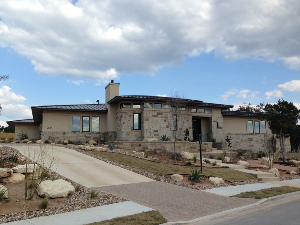 This is an example of a large and beige contemporary bungalow house exterior in Austin with stone cladding and a hip roof.