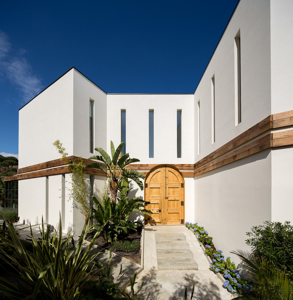Modelo de fachada blanca mediterránea grande de dos plantas con revestimiento de estuco y tejado plano