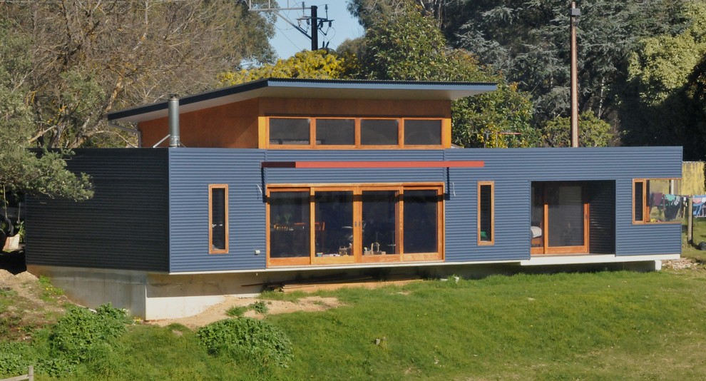 Foto de fachada azul actual de tamaño medio de una planta con revestimiento de metal y tejado plano