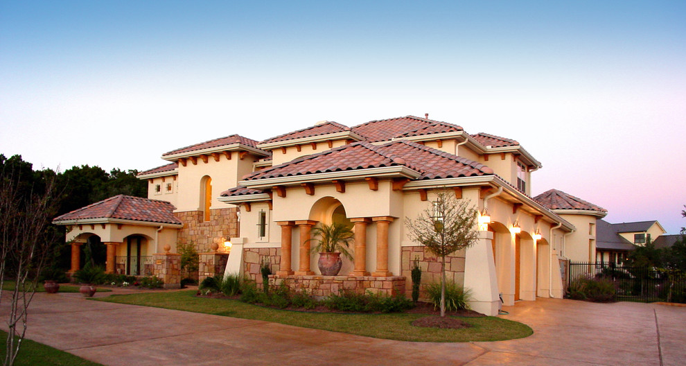 Inspiration for a large mediterranean beige two-story stucco exterior home remodel in Austin with a hip roof