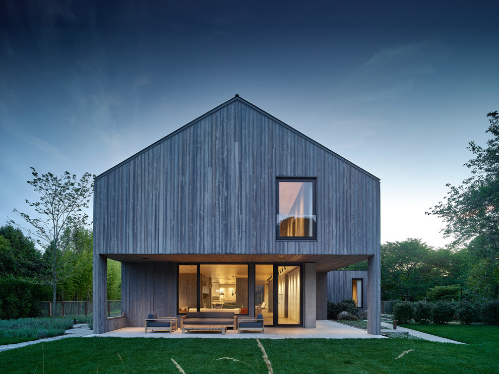 Gey rural two floor house exterior in New York with wood cladding and a pitched roof.