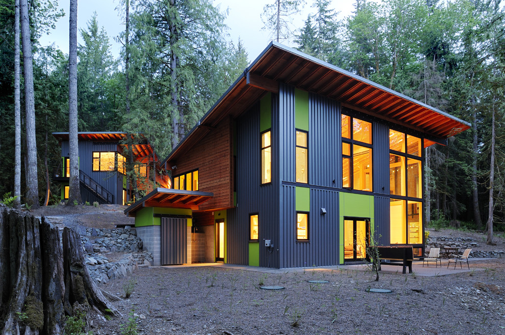 Réalisation d'une grande façade de maison multicolore design à un étage avec un toit en appentis et un revêtement mixte.