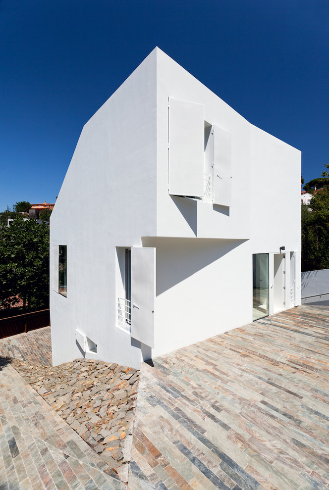 Cette image montre une façade de maison blanche design en stuc de taille moyenne et à un étage.
