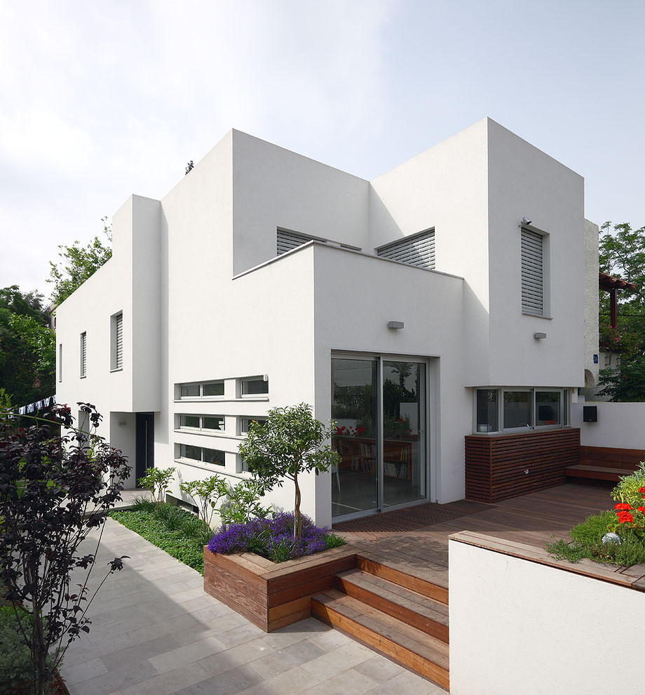 Cette image montre une petite façade de maison blanche minimaliste en stuc à niveaux décalés avec un toit plat.