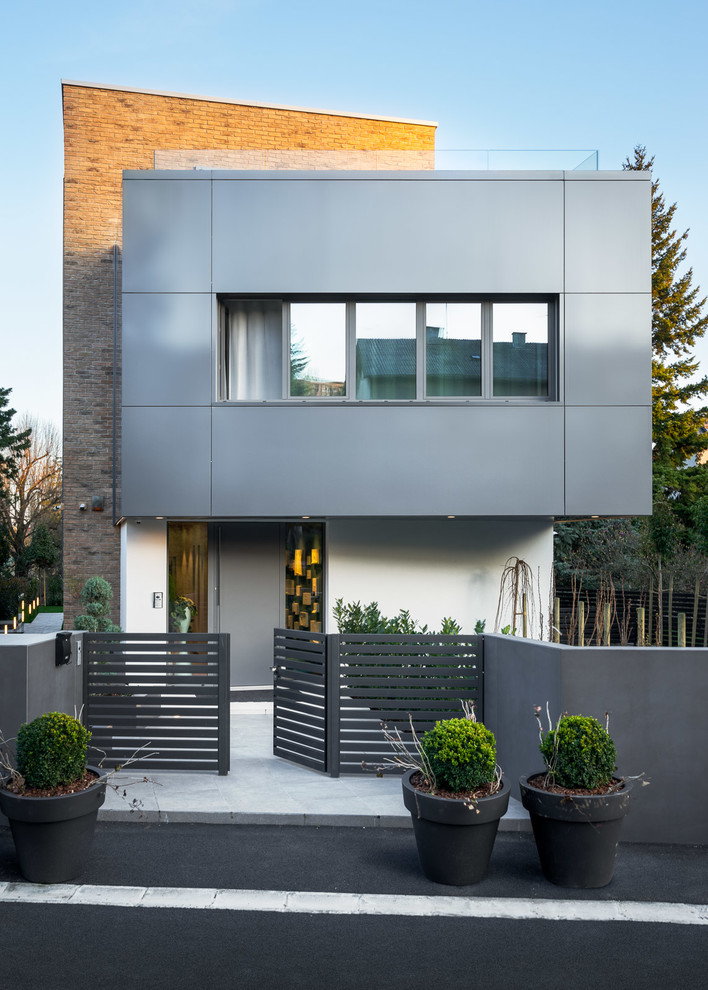 Cette photo montre une façade de maison grise tendance à un étage avec un revêtement mixte et un toit plat.