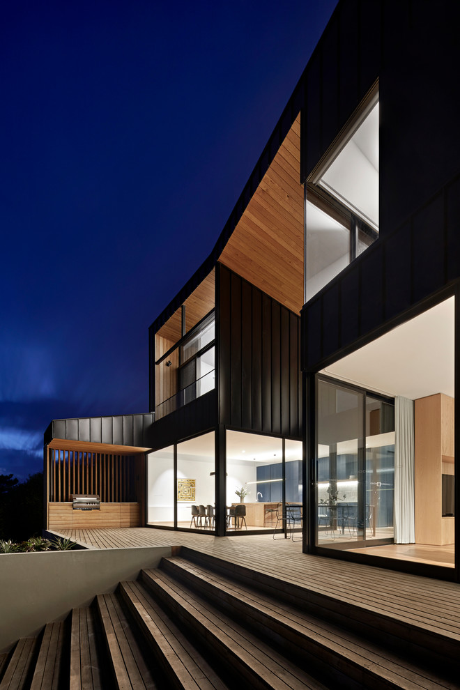 Idées déco pour une grande façade de maison métallique et noire moderne à niveaux décalés avec un toit en métal.