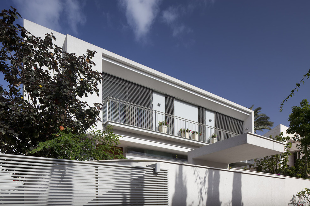 Expansive and white modern render house exterior in Tel Aviv with three floors and a flat roof.